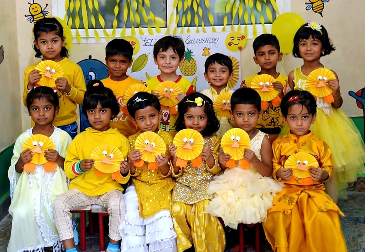 Naaz pre-school children holding yellow paper craft they made for a theme day